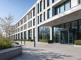 Modernes Verwaltungsgebäude mit Glasfassade und Vorplatz